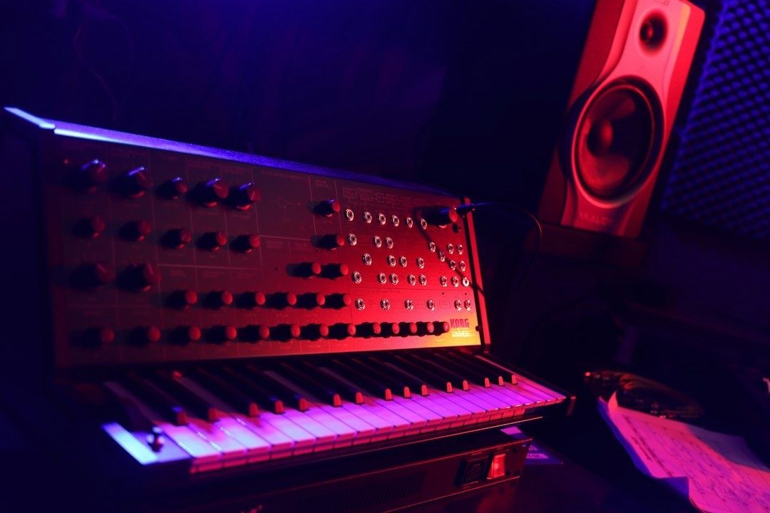 Retroanalog synthesizer med klaviatur och högtalare i färgat ljus